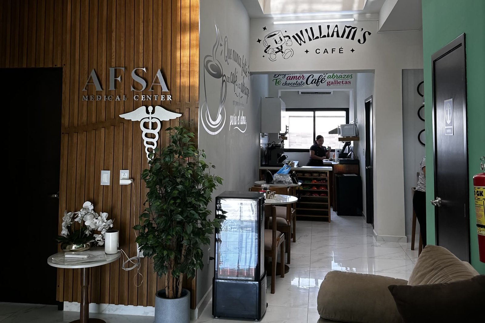 Recepción del centro médico con la entrada de Williams Café al fondo.